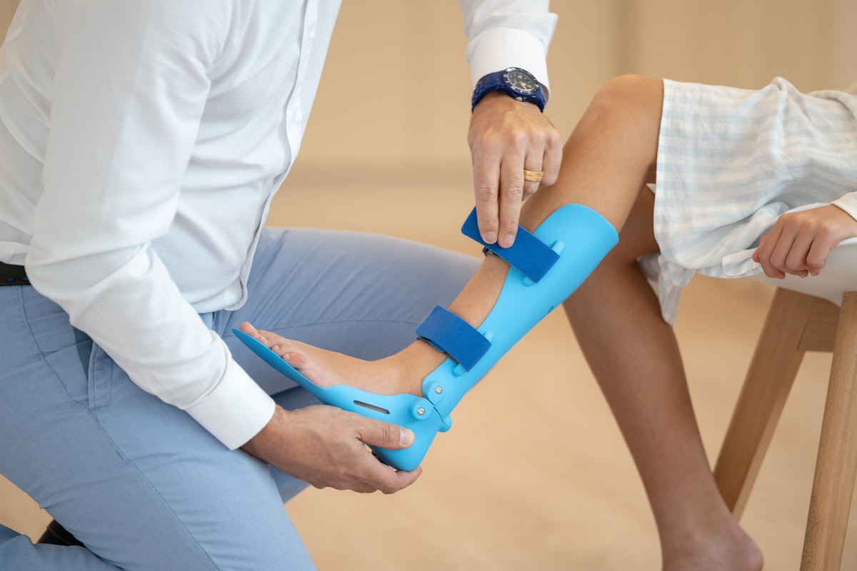 Fizjoterapeuta zakłada aplikację kinesiotapingu na nodze pacjenta